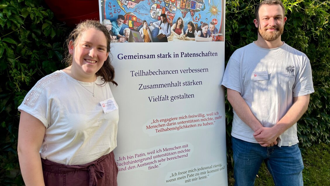 Innovations-Sofa Menschen stärken Menschen Zwei Menschen lächeln in die Kamera. Zwischen ihnen steht ein Transparent. - Das Innovations-Sofa. Diesmal mit dem Team von Menschen stärken Menschen der Caritas in Zwickau