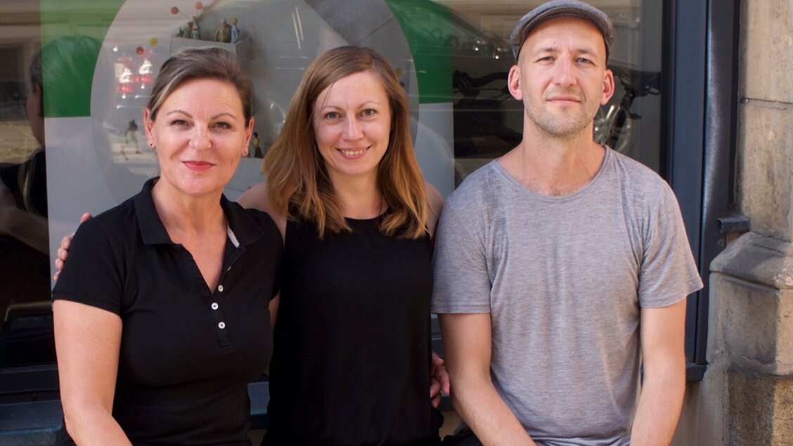 bring-together Gründungsteam Drei Menschen sitzen nebeneinander. Sie lächeln in die Kamera. - Das Innovations-Sofa. Diesmal mit dem Team von bring-together