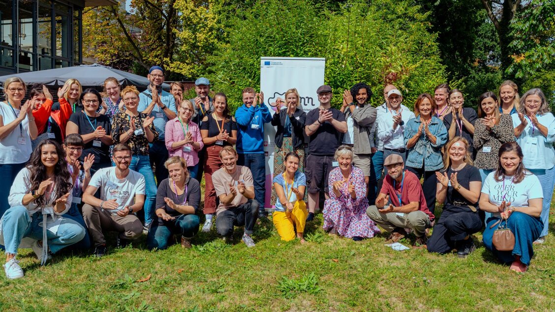 SINNkubator 4 Kickoff Eine große Gruppe an Menschen steht und kniet auf einer Wiese. Die Menschen lächeln in die Kamera. - Viele neue Gesichter - der SINNkubator geht in Runde 4