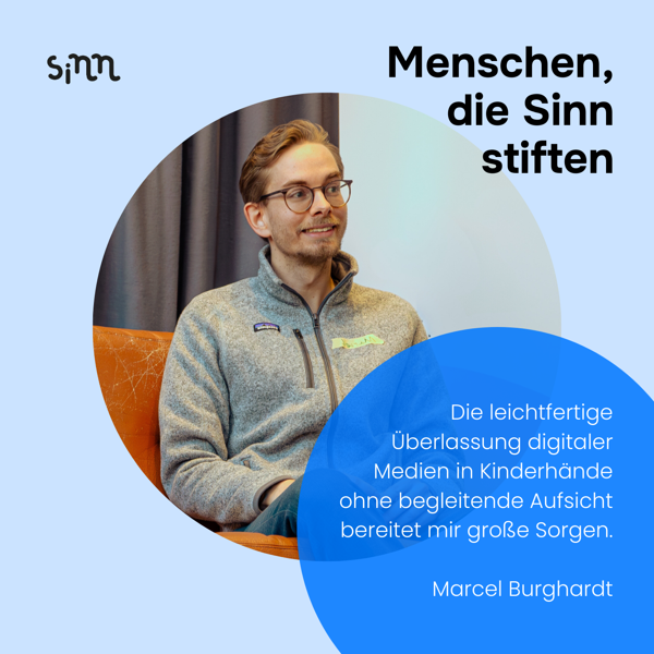 Ein Mann sitzt auf einem Sofa und lächelt.