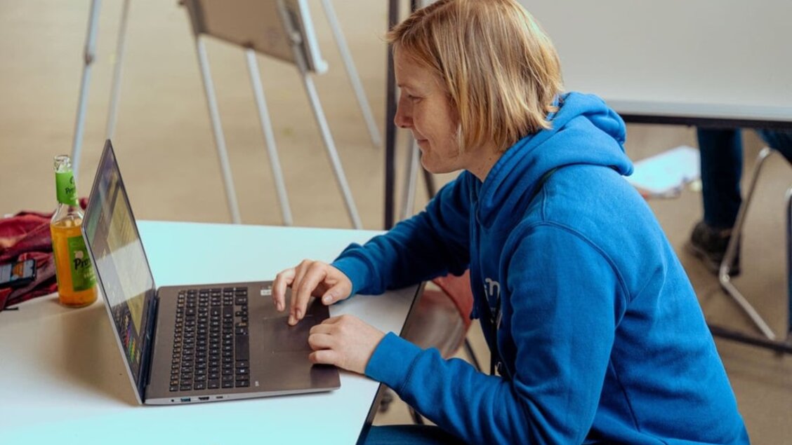 Eine Frau sitzt an einem Laptop. Sie ist von der Seite zu sehen. - SINN Online-Werkstatt - digitales Treffen für eure Anliegen