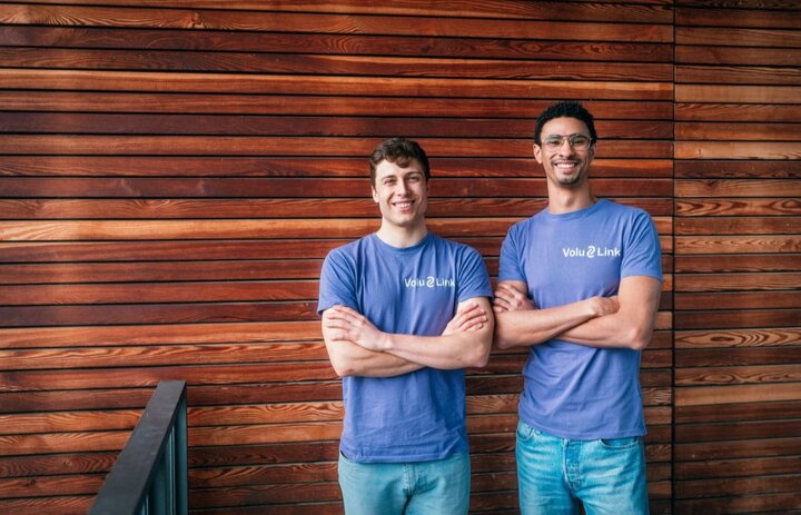 Zwei Männer lächeln in die Kamera. Sie haben die Arme überkreuzt. Im Hintergrund ist eine holzvertäfelte Wand. - Link: Das Innovations-Sofa. Diesmal mit Moritz Hall von VoluLink