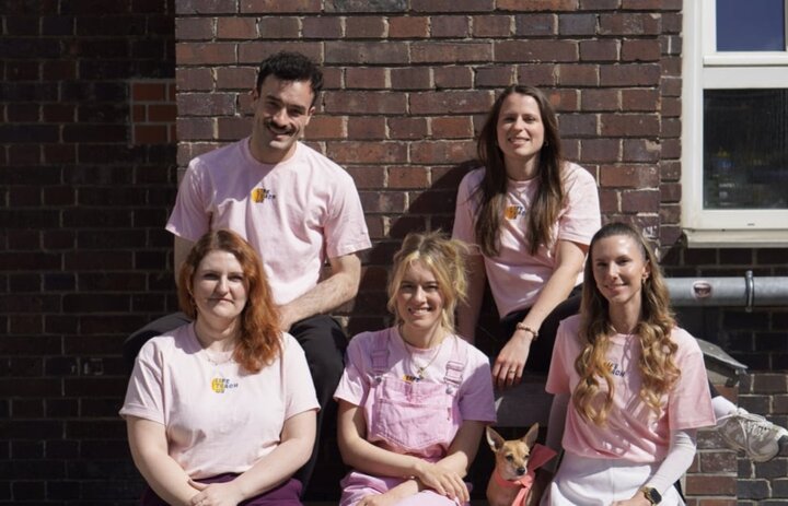 Fünf menschen in Rosa Shirts sitzen vor eine Wand. Sie lächeln in die Kamera. - Link: Das Innovations-Sofa. Diesmal mit LifeTeachUs