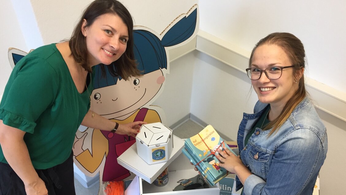 Innovations-Sofa wikilino Zwei Frauen haben Hefte und eine Pappbox in der Hand. Sie lächeln in die Kamera. - Das Innovations-Sofa. Diesmal mit dem Team von wiKilino